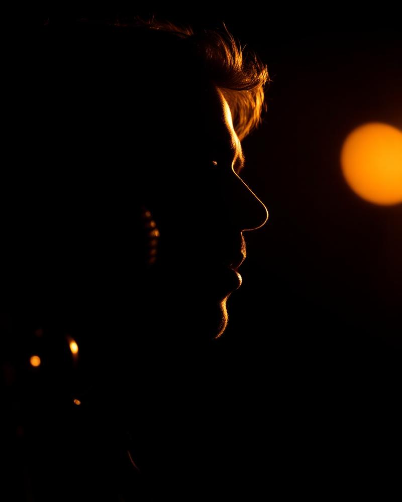 Silhouette of a soul vocalist at a vintage microphone in gold rim light