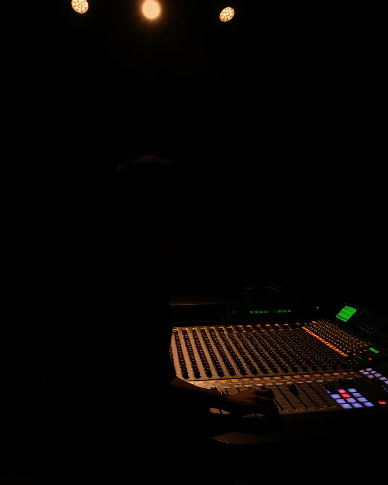 Silhouette of a producer at an analog mixing console